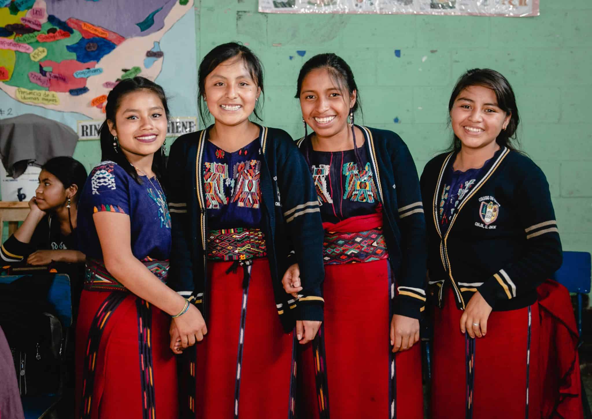 Group of smiling Ixil girls in traditional clothing at About Us event.