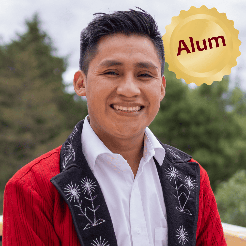 Young Ixil graduate smiling outdoors, celebrating academic achievement.