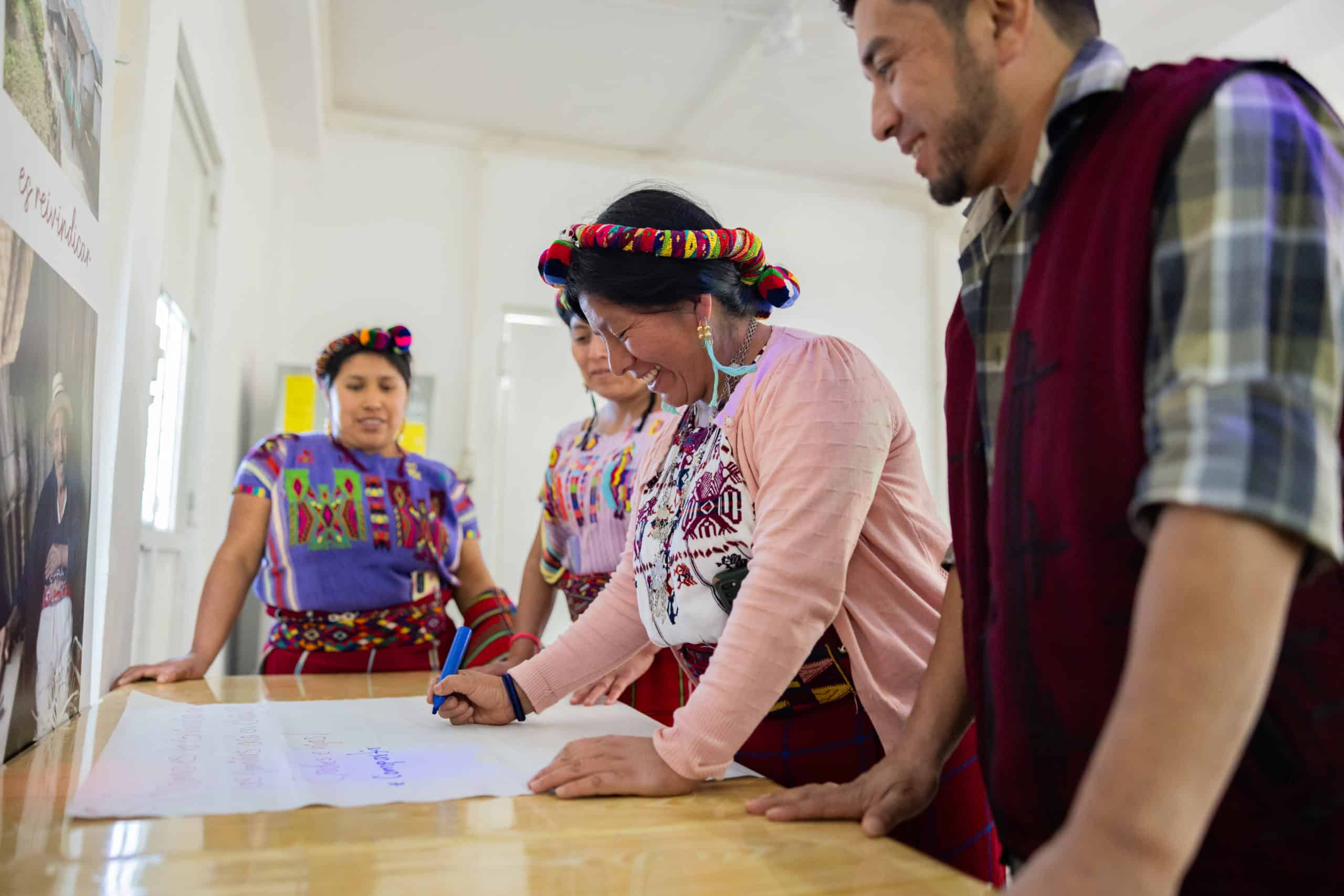 Teachers and students in traditional Ixil clothing collaborating at Colegio Horizontes.