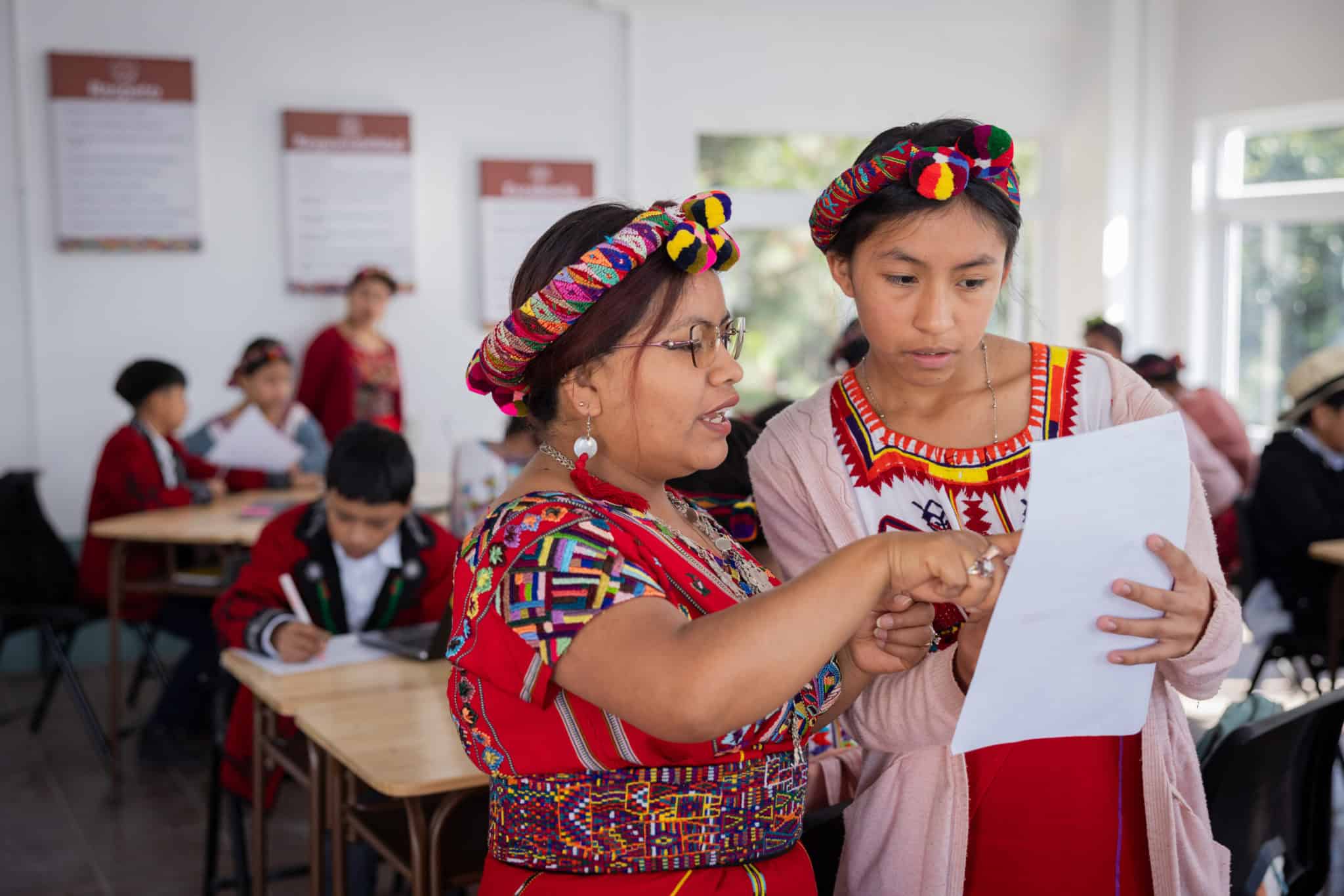 Mujer y niña ixil en aula, participando en actividades educativas en Colegio Horizontes.