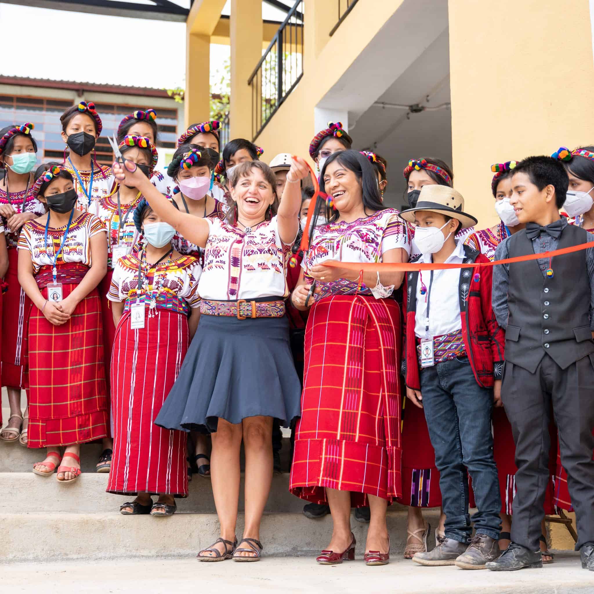 Indigenous community celebrating cultural event with traditional attire and joyful expressions.