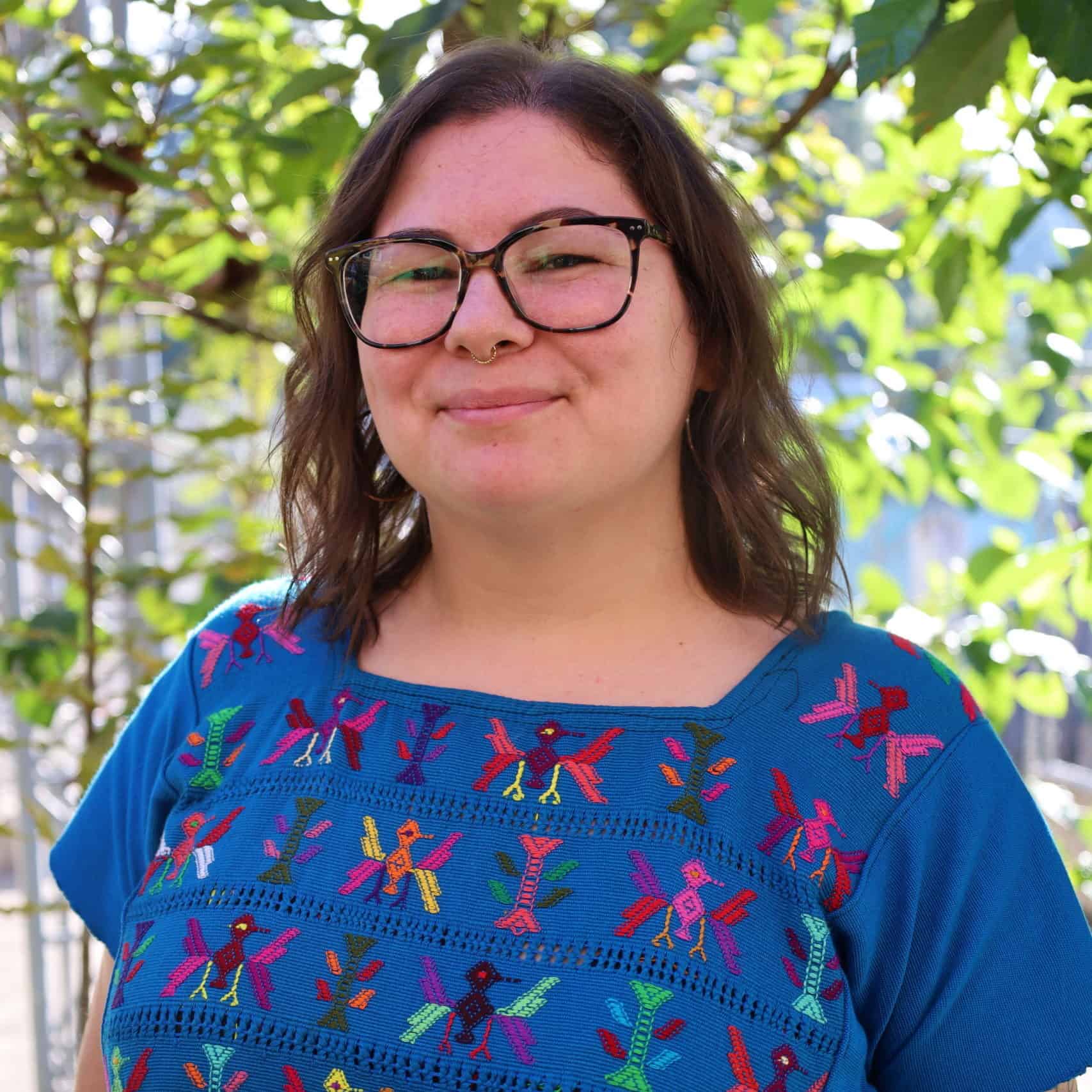 Marissa Cudworth smiling outdoors with greenery in the background, promoting education in Ixil commu.